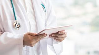 Doctor in a white coat holding a tablet.