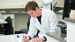 Male pharmacy student reads a label on a bottle