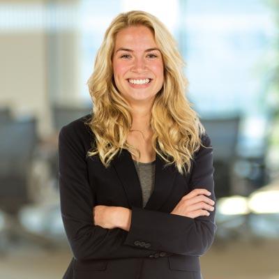 White female looking at camera and smiling with her arms crossed inside of a building