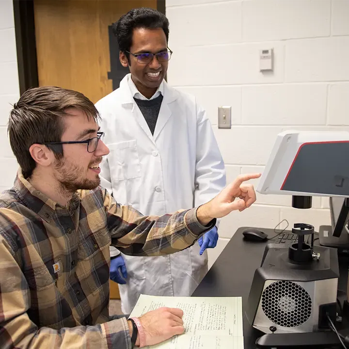 Two men working at a microscope.